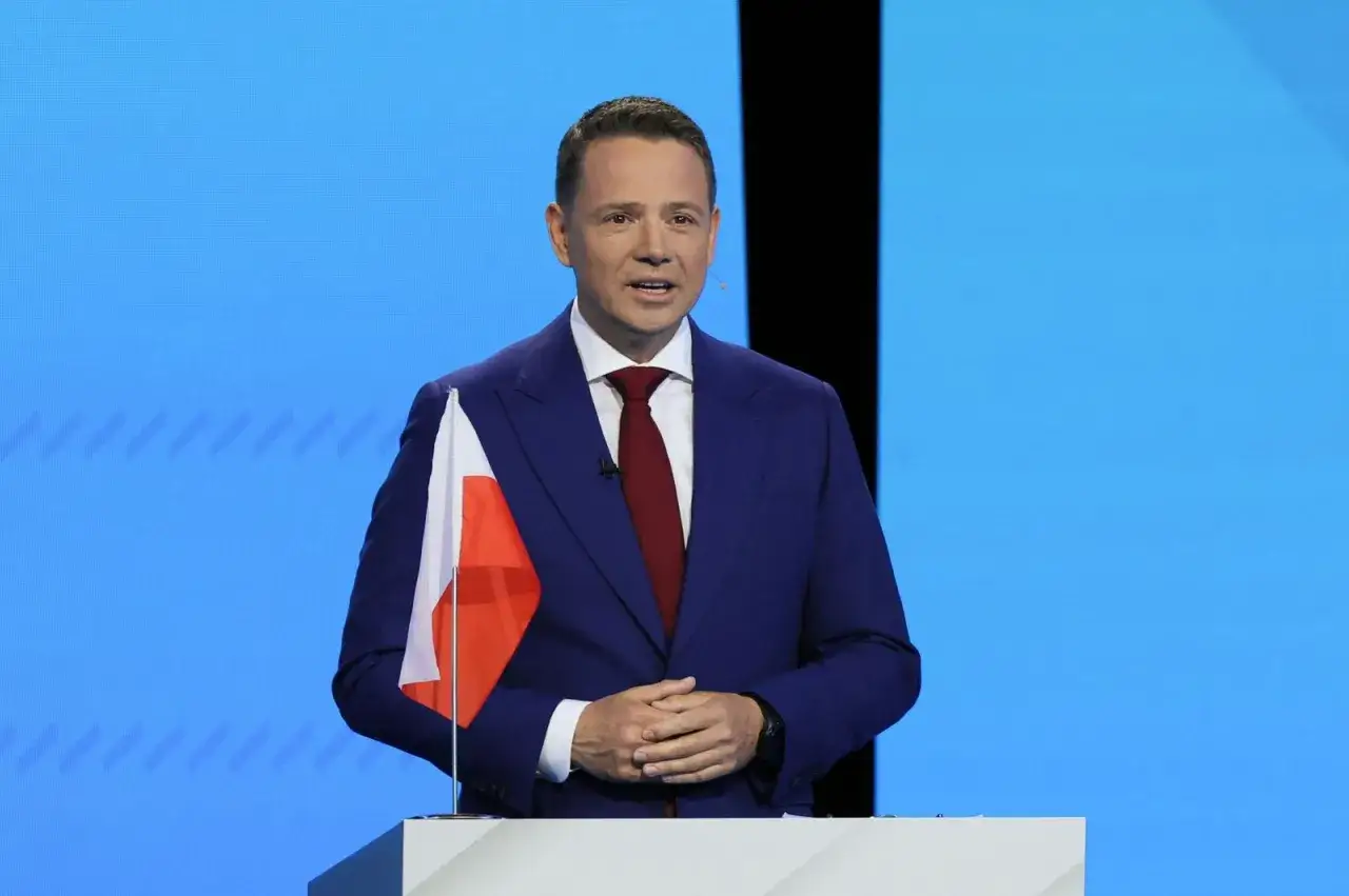 Rafał Trzaskowski, z polską flagą obok, przemawia. Jego doktorat jest dowodem jego zaangażowania w rozwój naukowy.