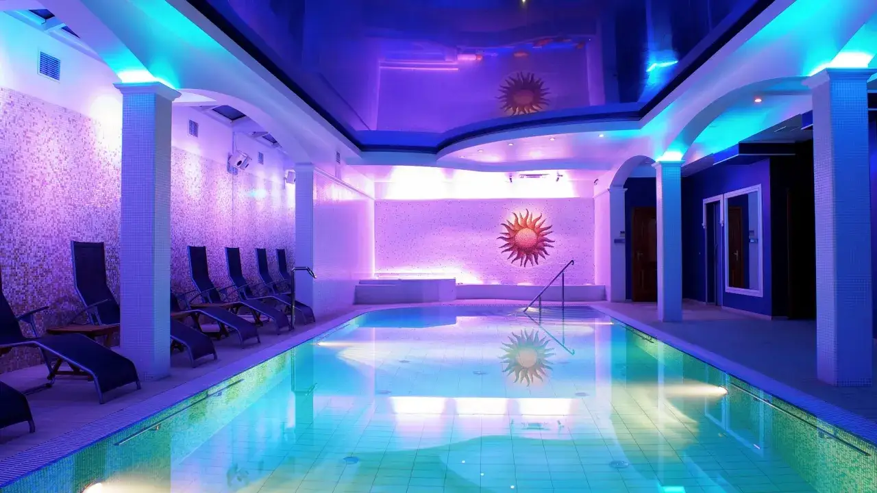 Relaks w hotelowych basenach pod błękitnym niebem. Luksusowe baseny w hotelu z kolorowym oświetleniem i leżakami.
