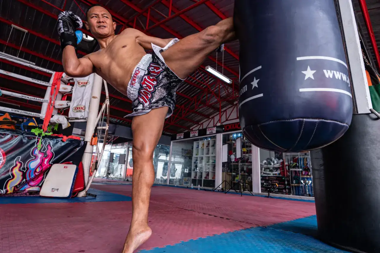 A Muay Thai fighter demonstrates his powerful kick, asking