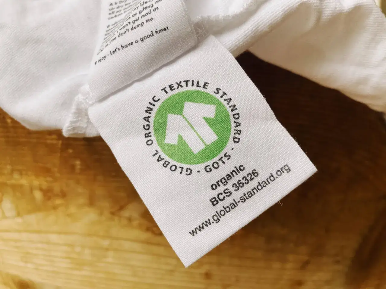 GOTS-zertifiziertes Textiletikett auf weißem Stoff. Keine Kritik, nur die Garantie für Bio-Qualität.