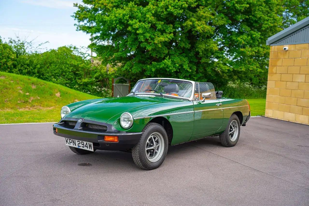 Grüner MG Roadster, ein Klassiker der englischen Automarken der 1960er Jahre, parkt vor einer Scheune.