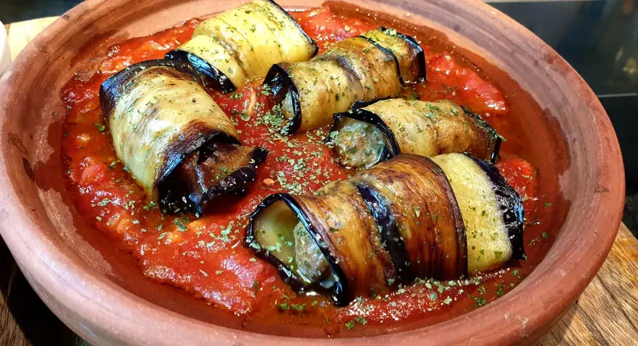 Rouleaux d'aubergine farcis à la viande hachée, baignant dans une sauce tomate savoureuse. Une délicieuse recette aubergine viande hachée.
