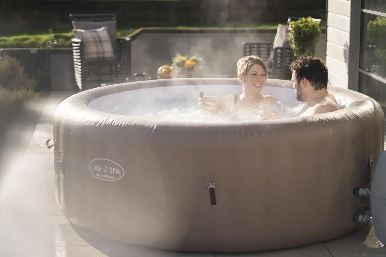 Para relaksu w jacuzzi Lay-Z-Spa Palm Springs. Para cieszy się gorącą kąpielą na tarasie.