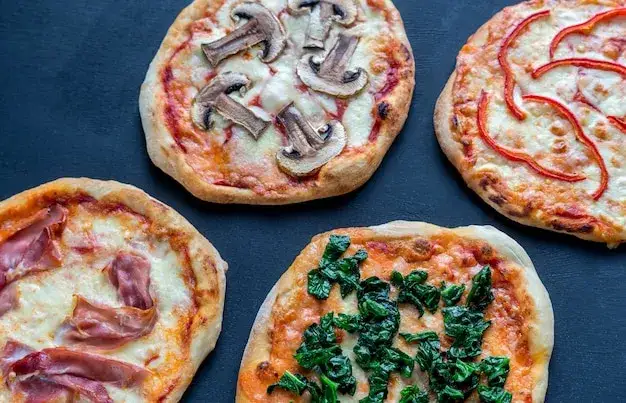 mini pizzas caseras variadas en una tabla de madera