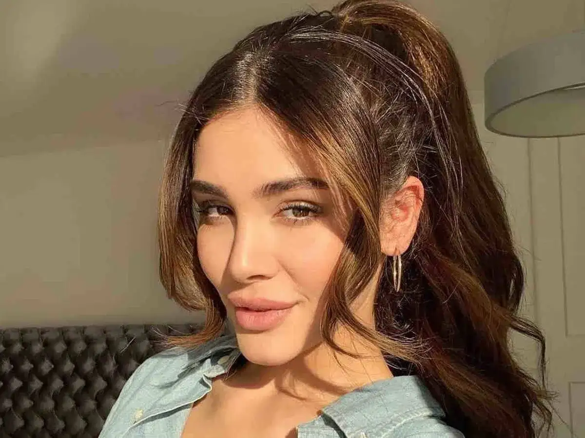 Mujer con coleta alta y mechones sueltos, un look que evoca los peinados de los 90.