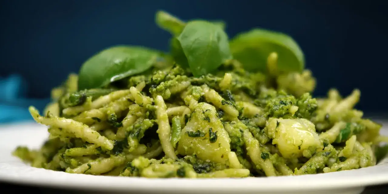 Pyszny makaron z pesto ze słoika, udekorowany świeżymi listkami bazylii.