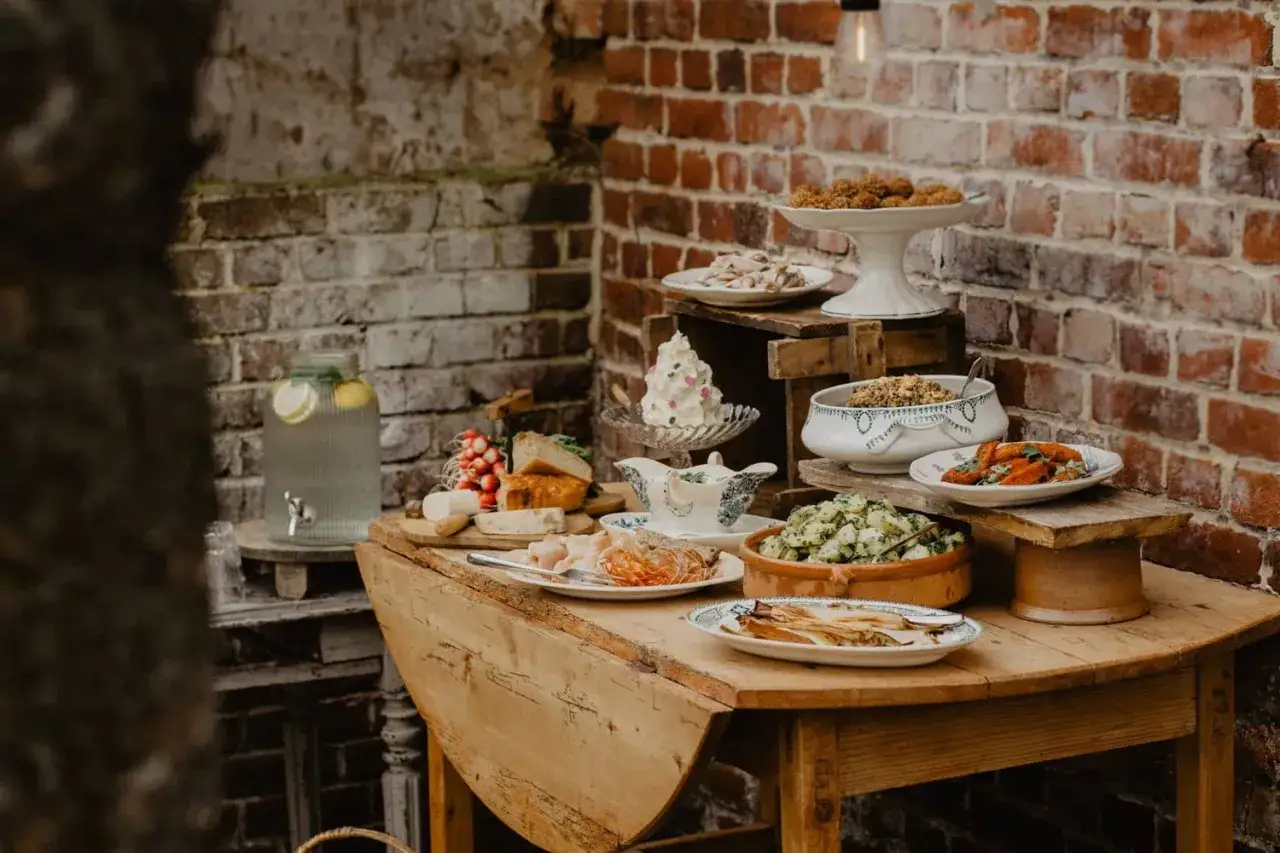 Un buffet campagnard pour 20 personnes : salades, charcuterie, fromages, pain, et une fontaine à eau citronnée.