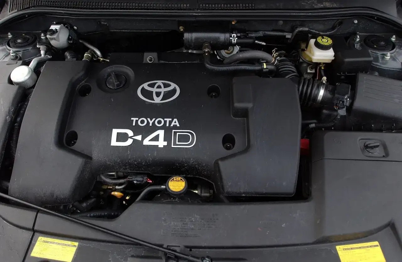 Silnik Toyota Avensis T25 2.0 D4D. Widoczny czarny plastik z logo Toyoty i napisem D4D.