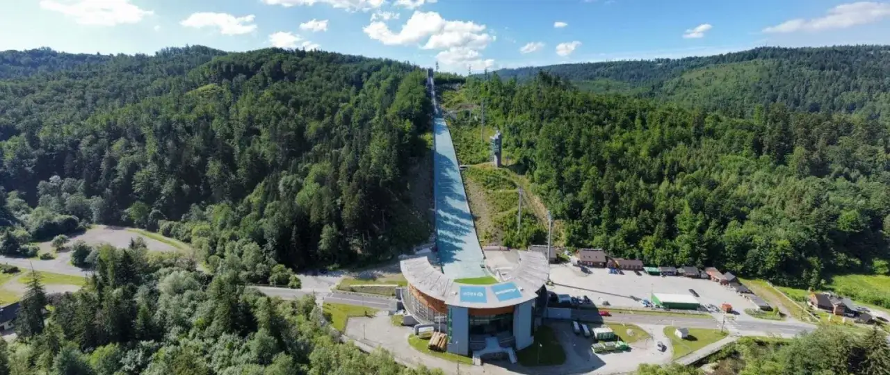 Skocznia narciarska w Wiśle, otoczona zielonymi lasami, gotowa na emocjonujące skoki.