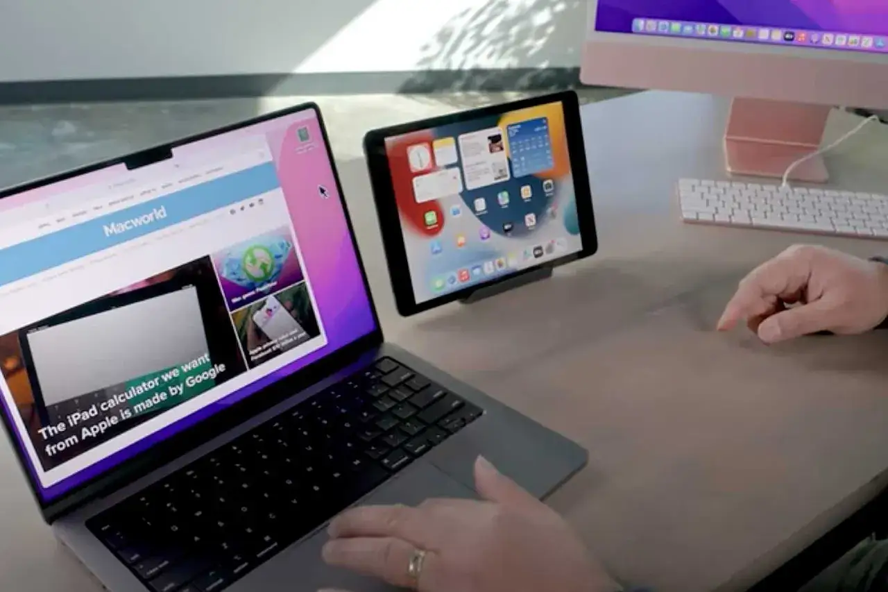 Ręka steruje laptopem i tabletem, pokazując potencjał uniwersalnego sterowania między urządzeniami Apple.