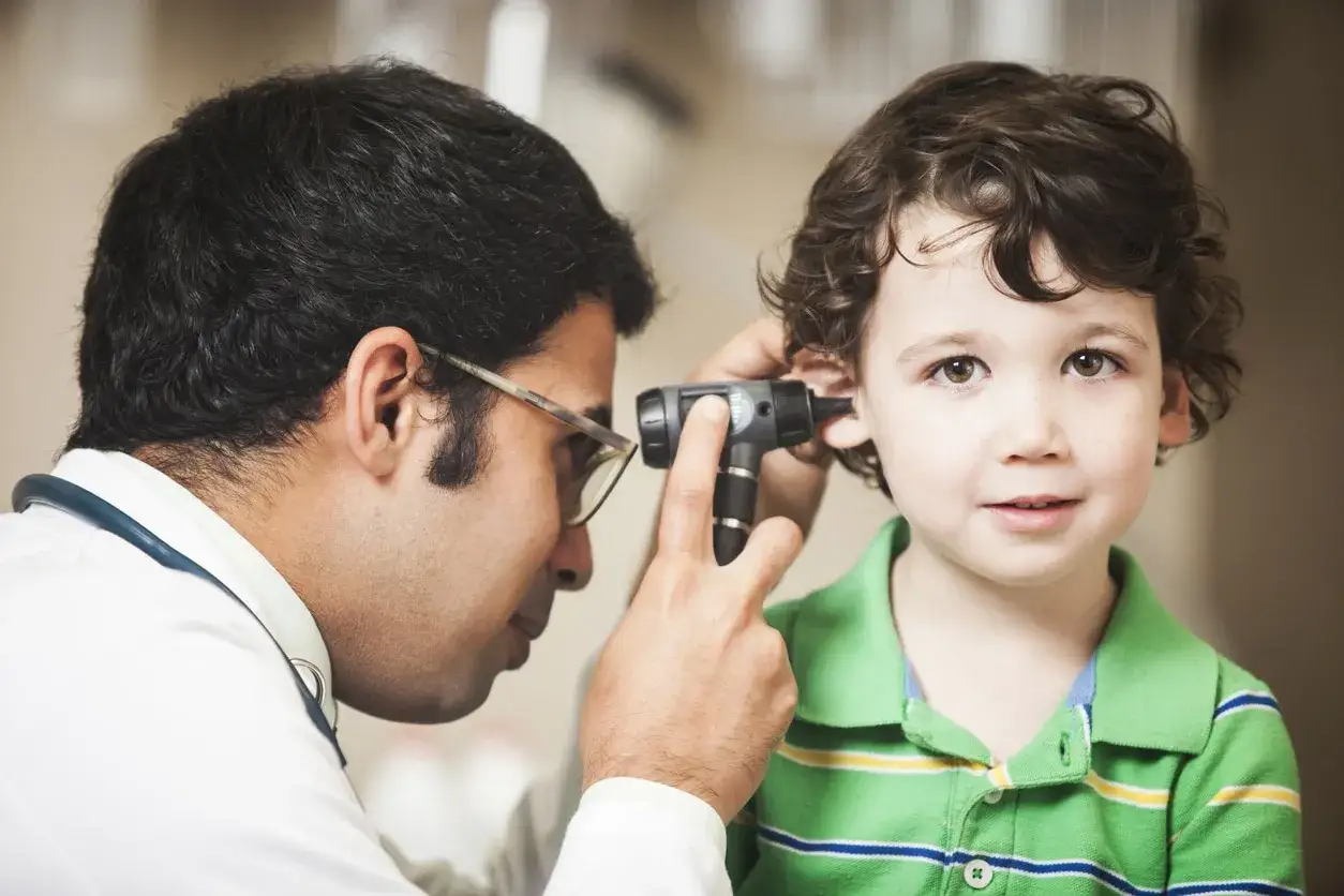 Lekarz bada ucho dziecka, diagnozując niedosłuch przewodzeniowy u dzieci.