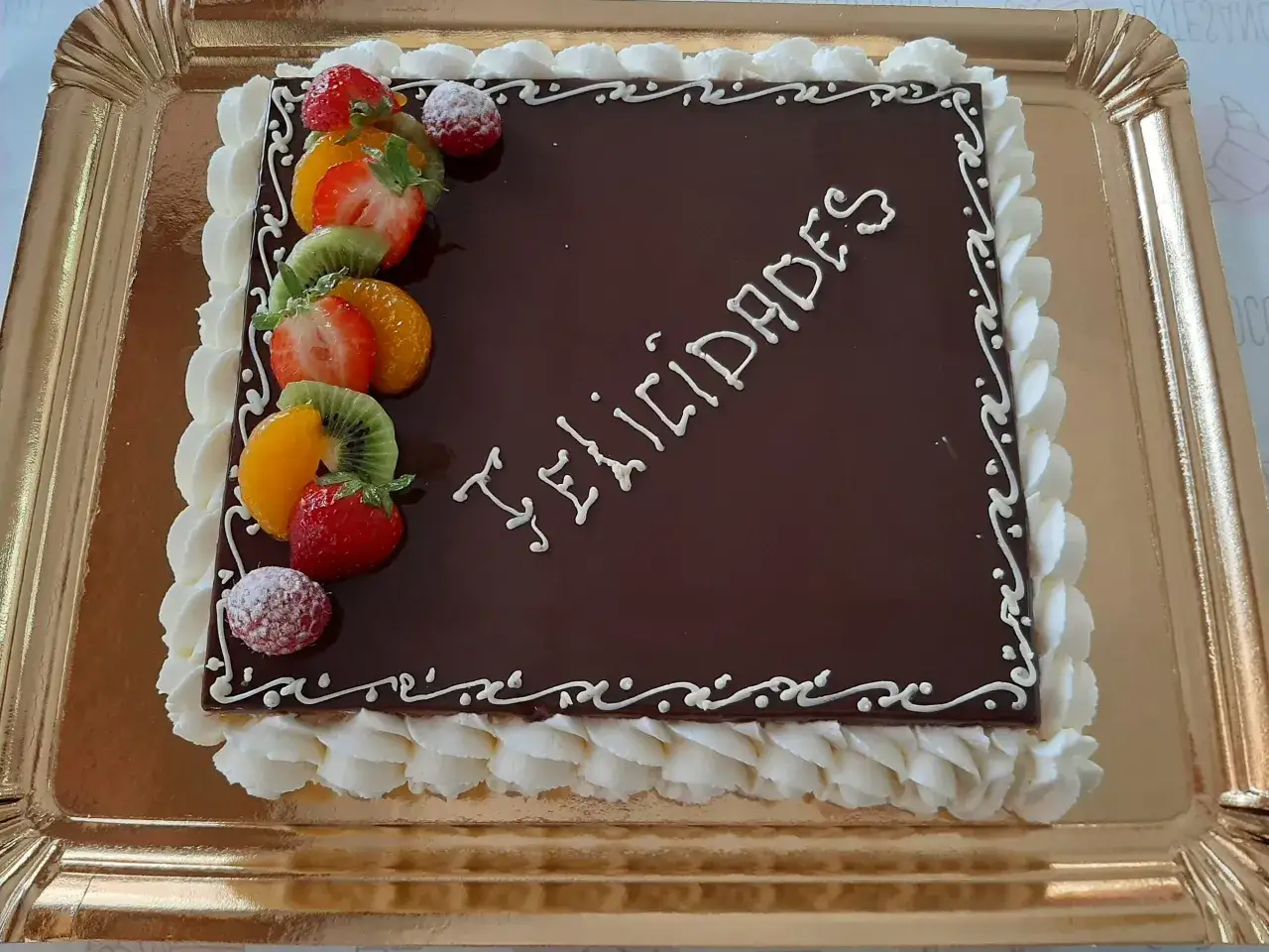 Pastel napolitano decorado con frutas frescas y glaseado blanco, con la palabra
