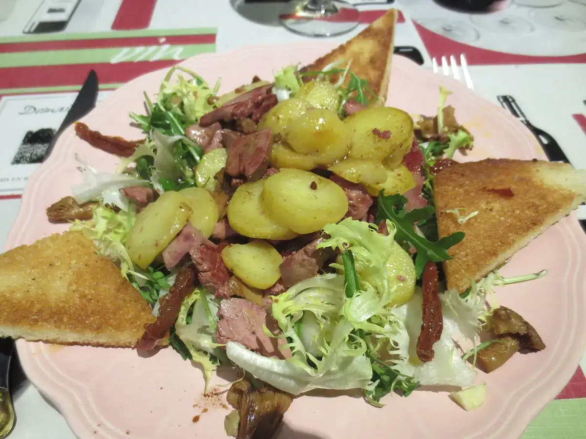 Salade périgourdine avec pommes de terre, magret, gésiers et toasts. Un plat qui met à l'honneur les spécialités culinaires Dordogne.