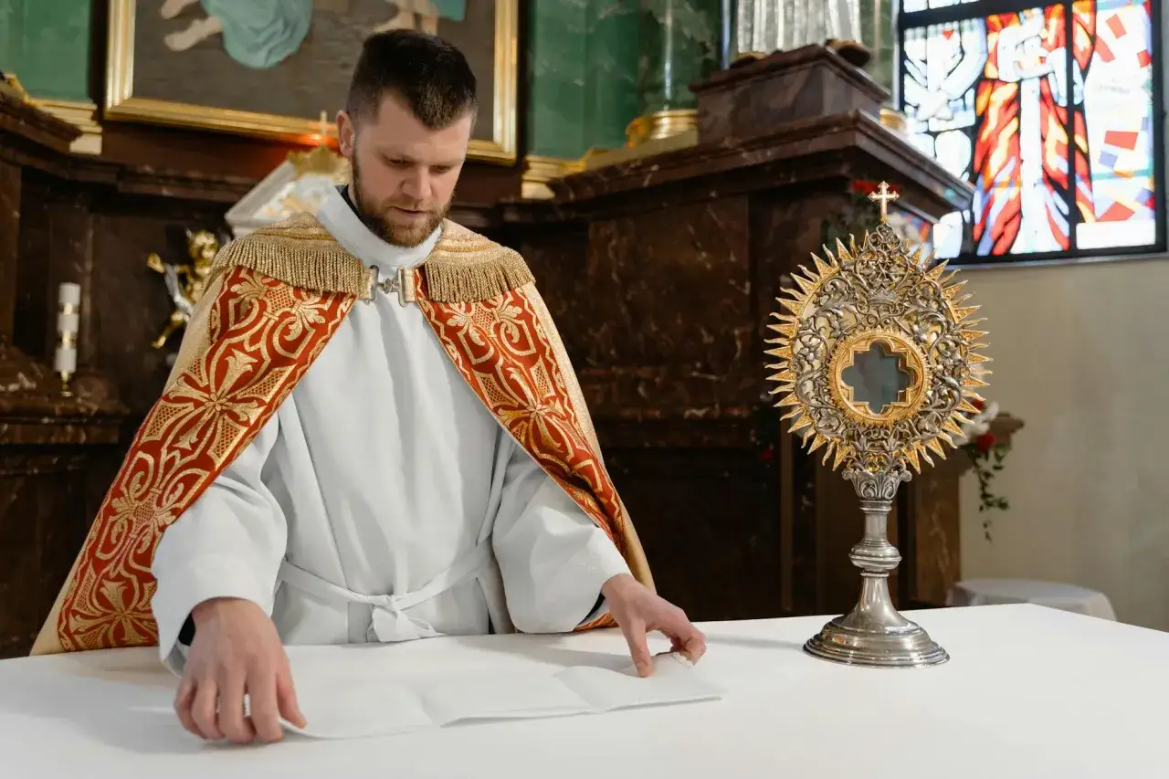 Kapłan w bogato zdobionej kapie przygotowuje się do adoracji Najświętszego Sakramentu. To ważny moment w katolicyzmie, odzwierciedlający głębię chrześcijaństwa.