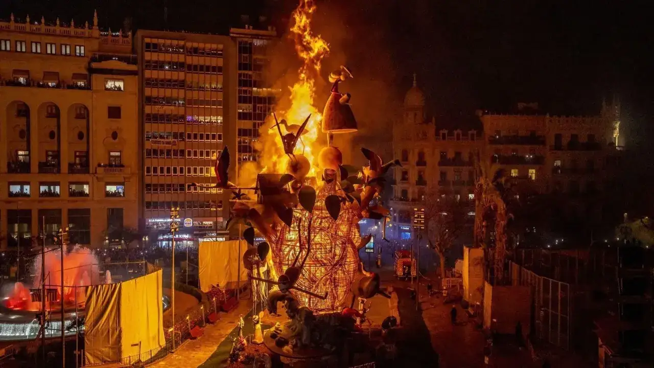 La **cremà** de las Fallas de Valencia ilumina la noche con un espectáculo de fuego. Monumentos artísticos arden en medio de edificios históricos.