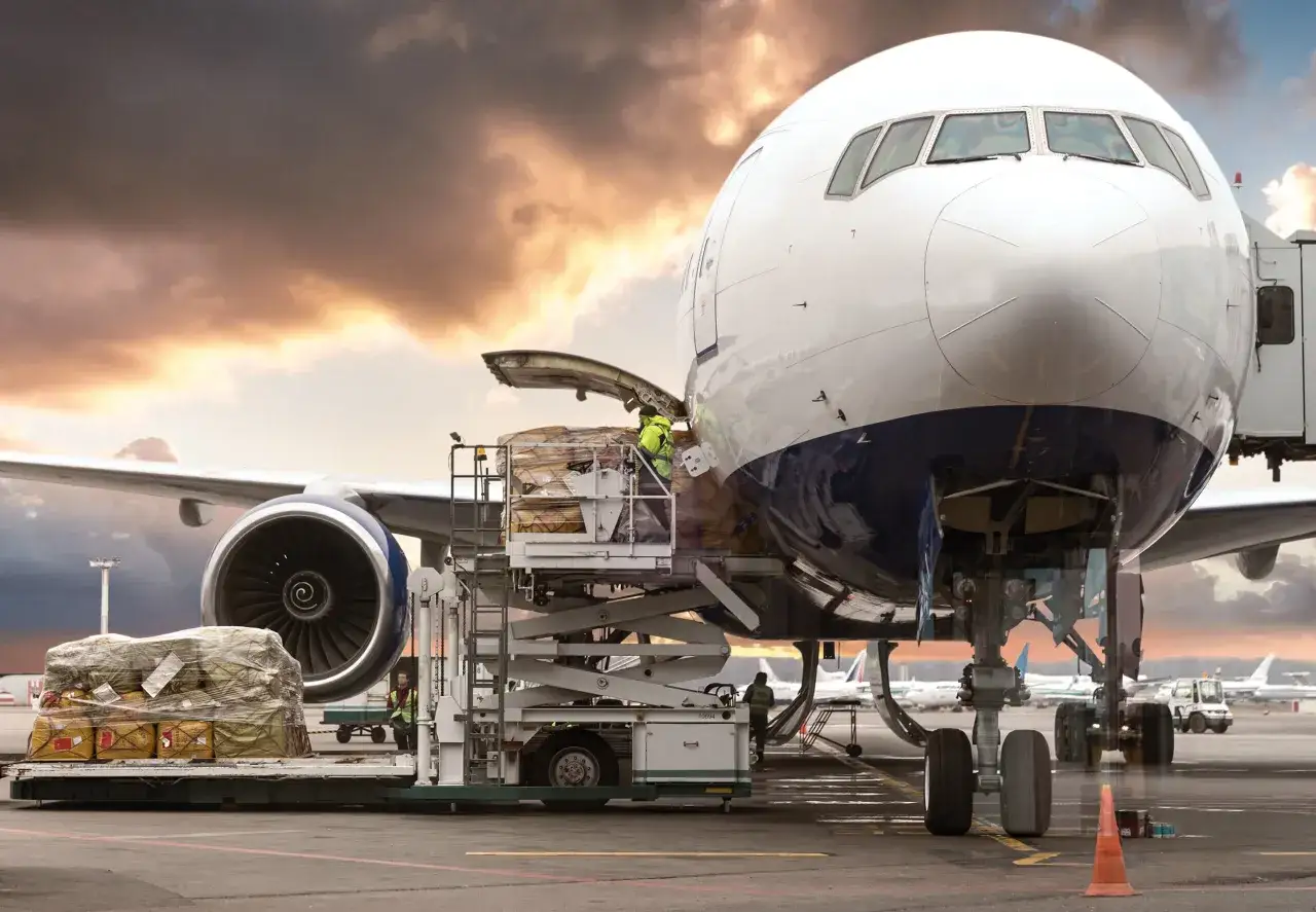 Frachtflugzeug wird beladen, w&auml;hrend die Sonne untergeht. Die IATA, die Internationale Luftverkehrs-Vereinigung, sorgt f&uuml;r sicheren und effizienten Luftverkehr.