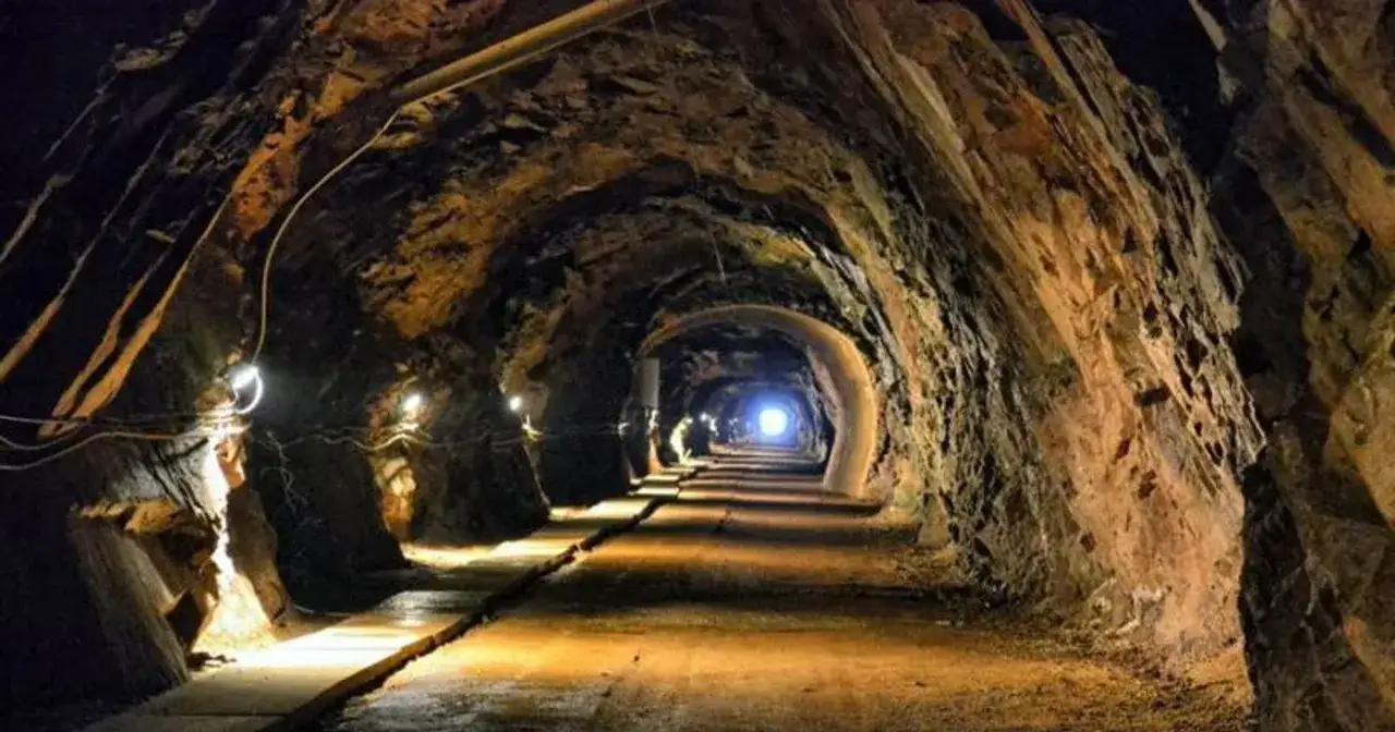 Wąski tunel oświetlony lampami, prowadzący w głąb ziemi. To jedne z wielu tajemniczych jaskiń Dolnego Śląska.