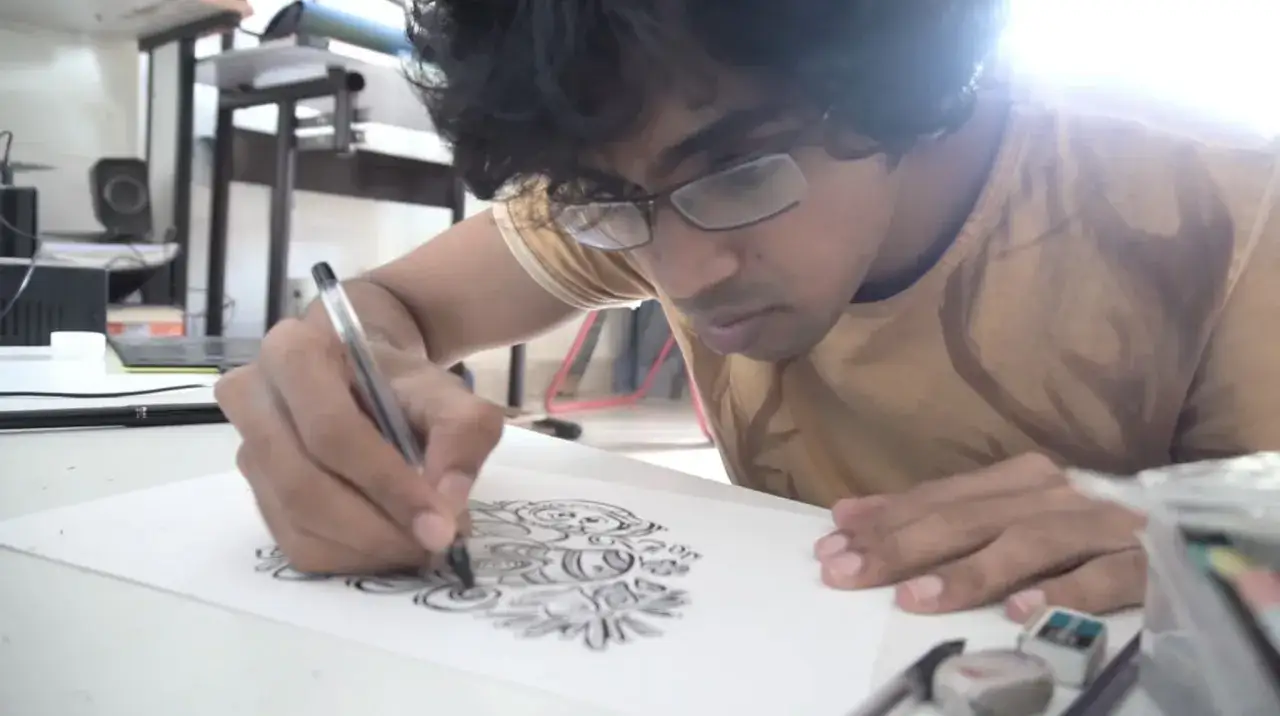 Un jeune homme concentr&eacute; r&eacute;alise un exercice de dessin complexe, son stylo tra&ccedil;ant des lignes fines sur le papier.