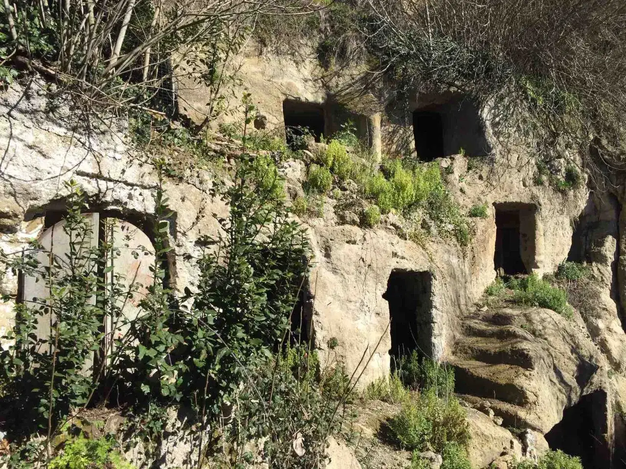 Antiche abitazioni scavate nella roccia, un luogo dove la **Calcata storia** rivive tra vegetazione e mistero.