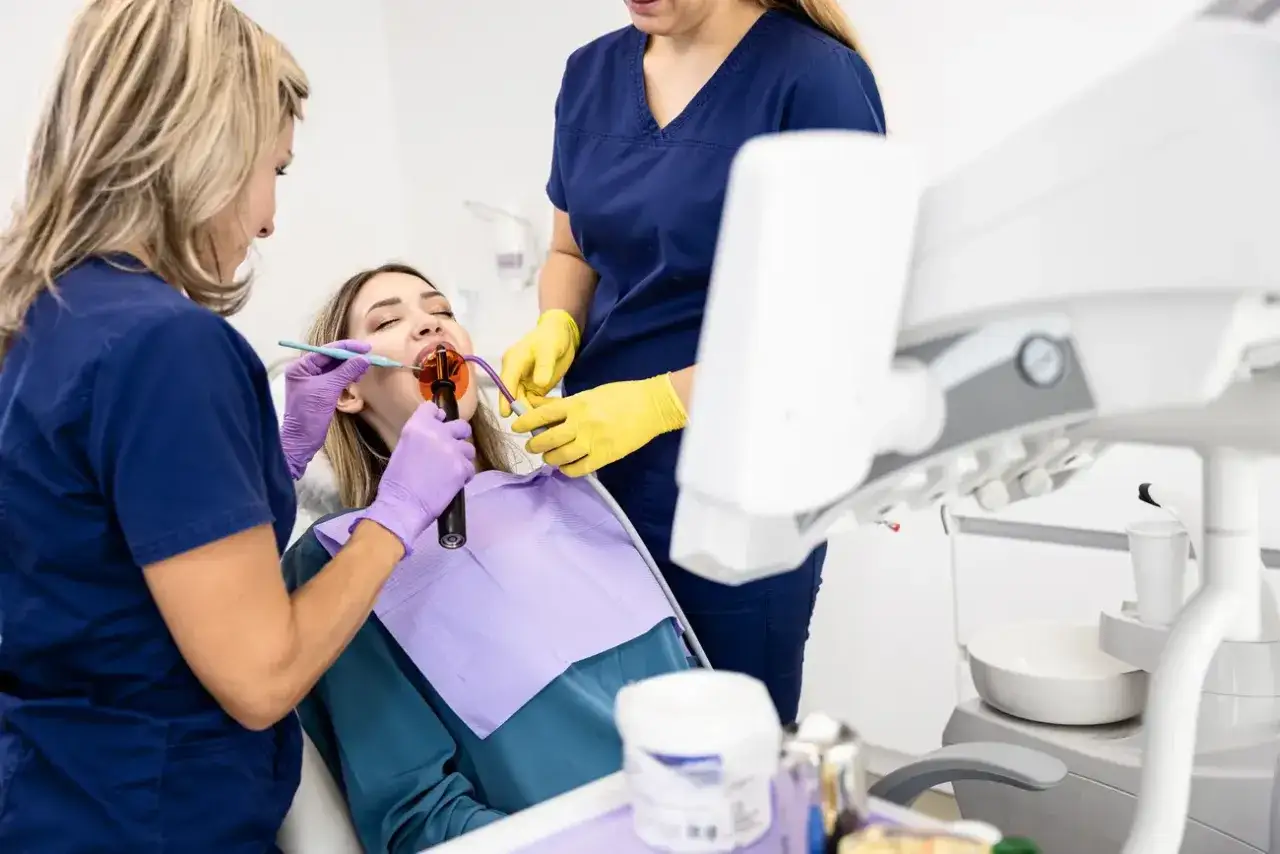 Pacjentka u dentysty, która odczuwa ból zęba po plombowaniu po miesiącu. Zabieg z użyciem lampy polimeryzacyjnej.