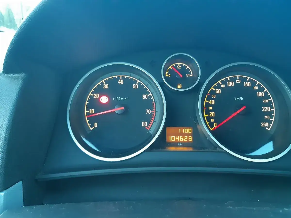 Deska rozdzielcza Opla Astry H. Widoczny obrotomierz, prędkościomierz, wskaźnik paliwa i przebieg 104623 km. Czas na kasowanie inspekcji.