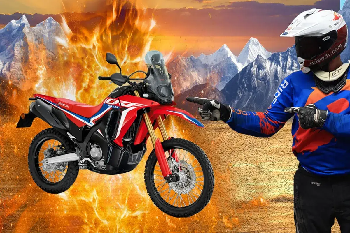 Motocyklista wskazuje na czerwony, lekki motocykl turystyczny Honda CRF300 Rally na tle płonących g&oacute;r i zaśnieżonych szczyt&oacute;w.