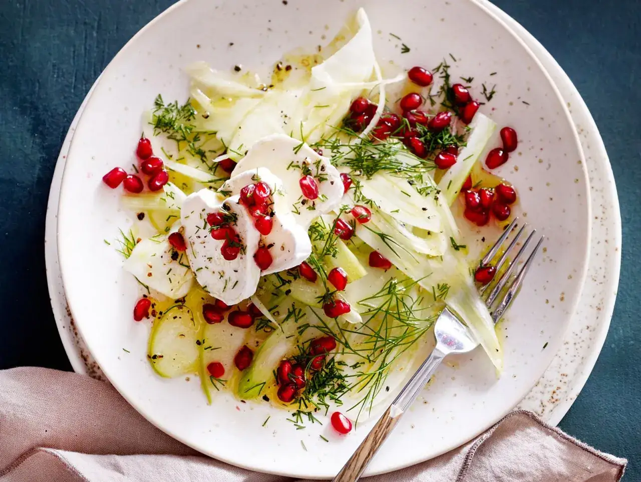 Erfrischender Fenchel Apfel Salat mit Granatapfelkernen und Ziegenk&auml;se, garniert mit Dill.
