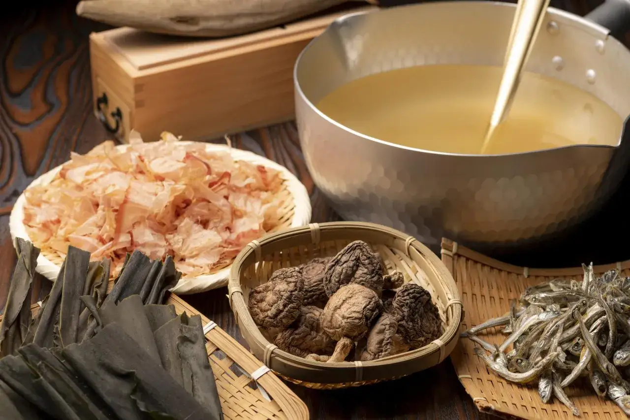 Składniki do dashi: suszone bonito, kombu, shiitake i sardelki. Gotowy bulion w garnku.