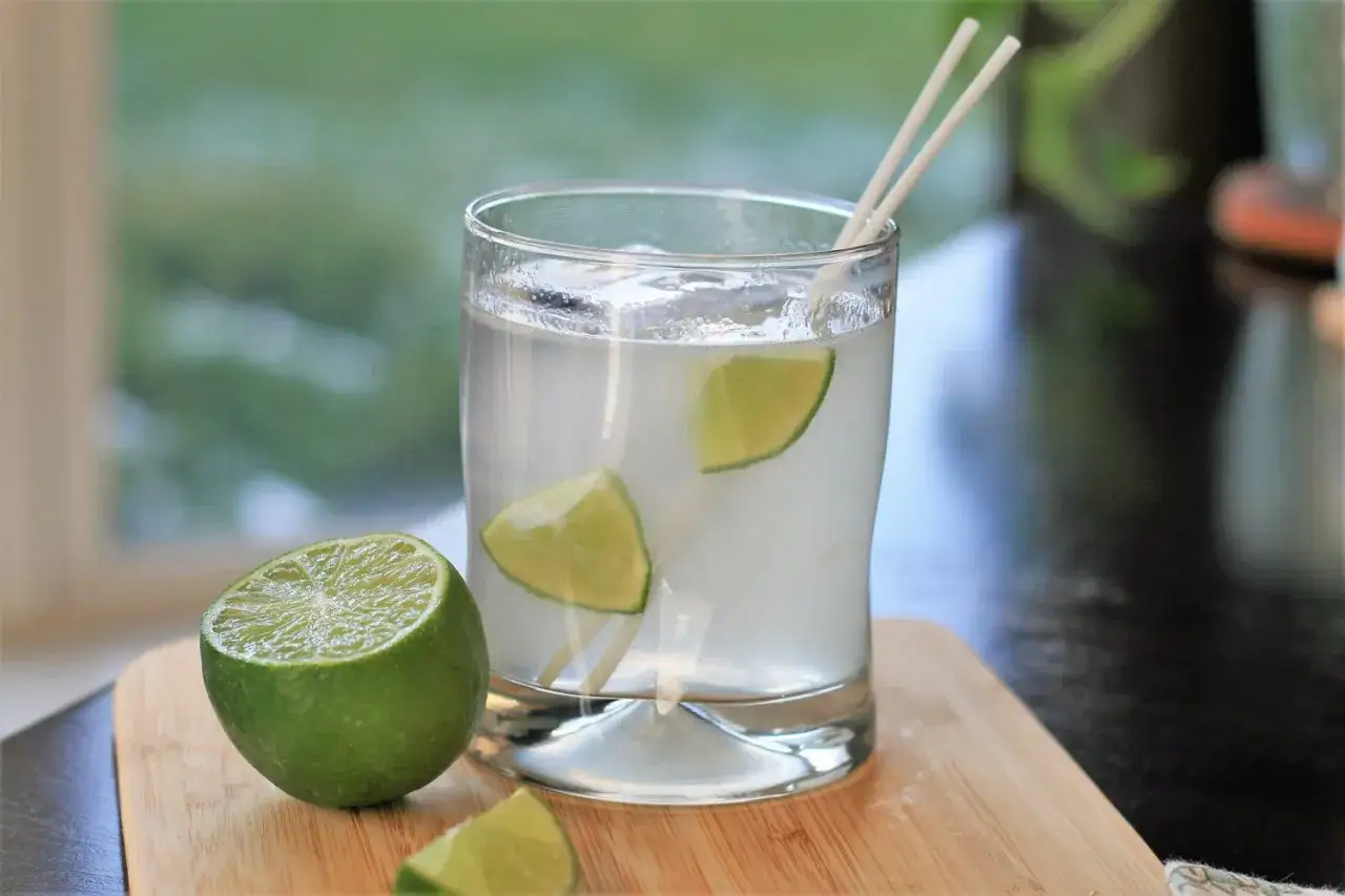 Ein erfrischender Gin Tonic, ein klassischer Cocktail, mit Limettenspalten und Eiswürfeln in einem Glas.