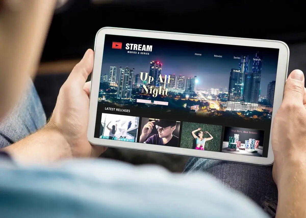 Osoba trzyma tablet, na którym wyświetla się aplikacja do oglądania filmów. Idealny tablet do oglądania filmów, z najnowszymi premierami.
