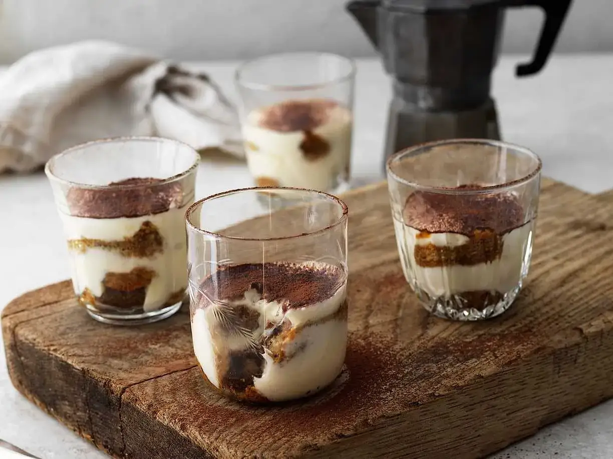 Fyra läckra tiramisu i glas, perfekt för en kaffepaus.