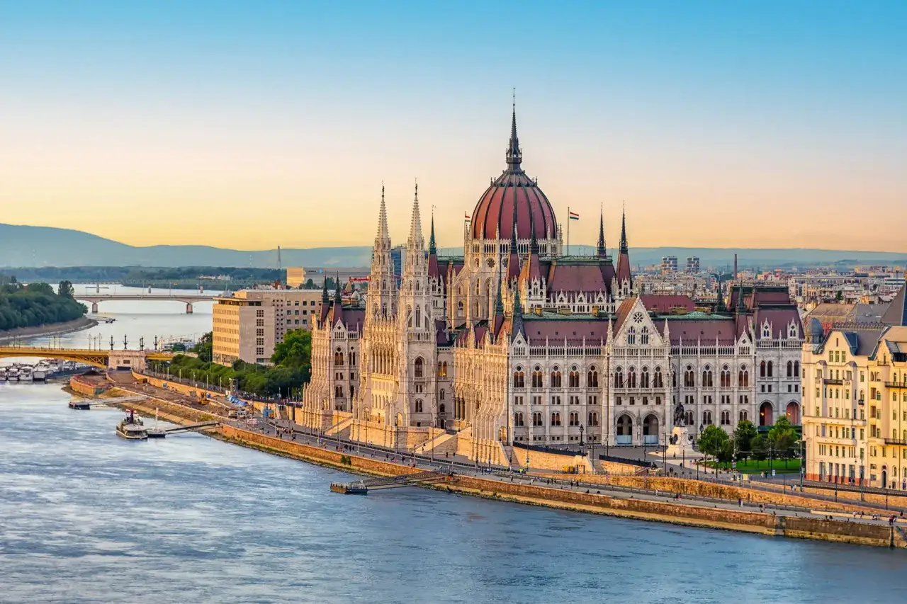 Budynek Parlamentu w Budapeszcie nad rzeką Dunaj, oświetlony porannym słońcem.