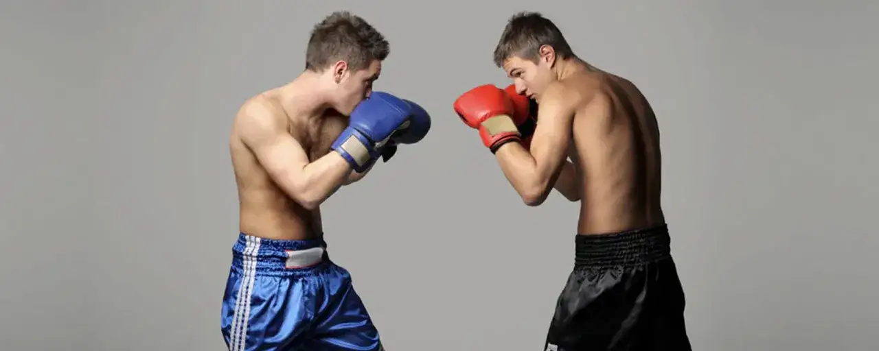 Two boxers in a ring, one with blue gloves and shorts, the other with red gloves and black shorts, showcasing their boxer puncher style.