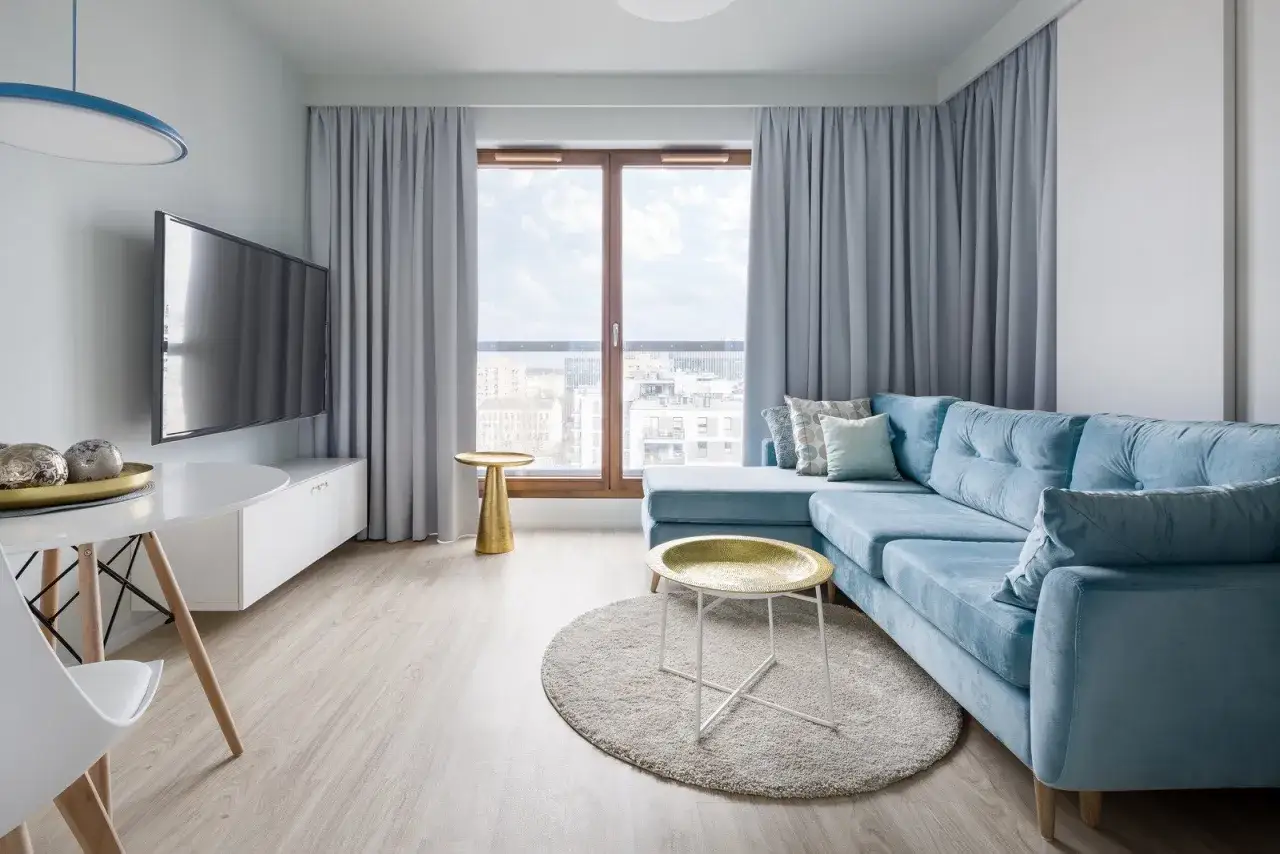Jasny salon z błękitną kanapą i złotymi dodatkami. Nowoczesny styl włoski we wnętrzach, który zachwyca lekkością i elegancją.