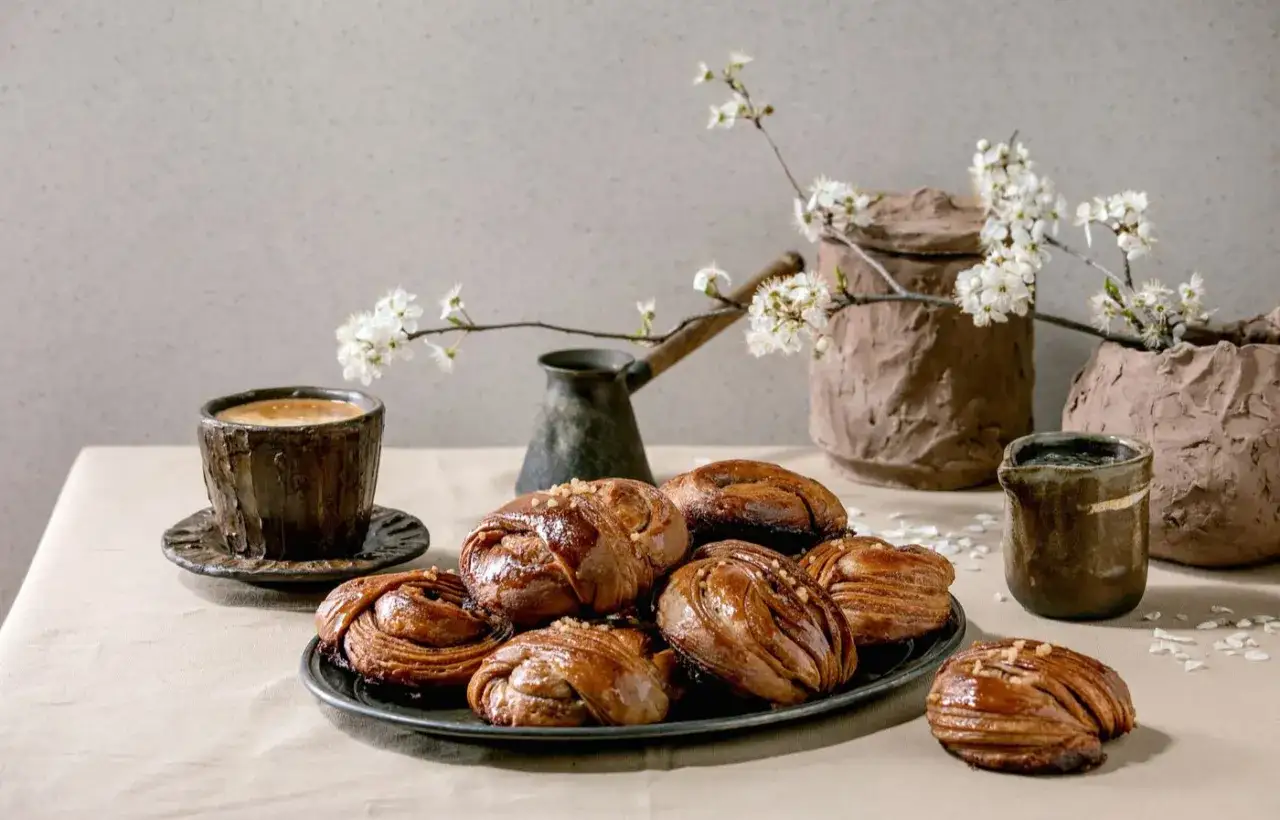 En härlig fika paus med nybakade kanelbullar, kaffe och vackra blommor.