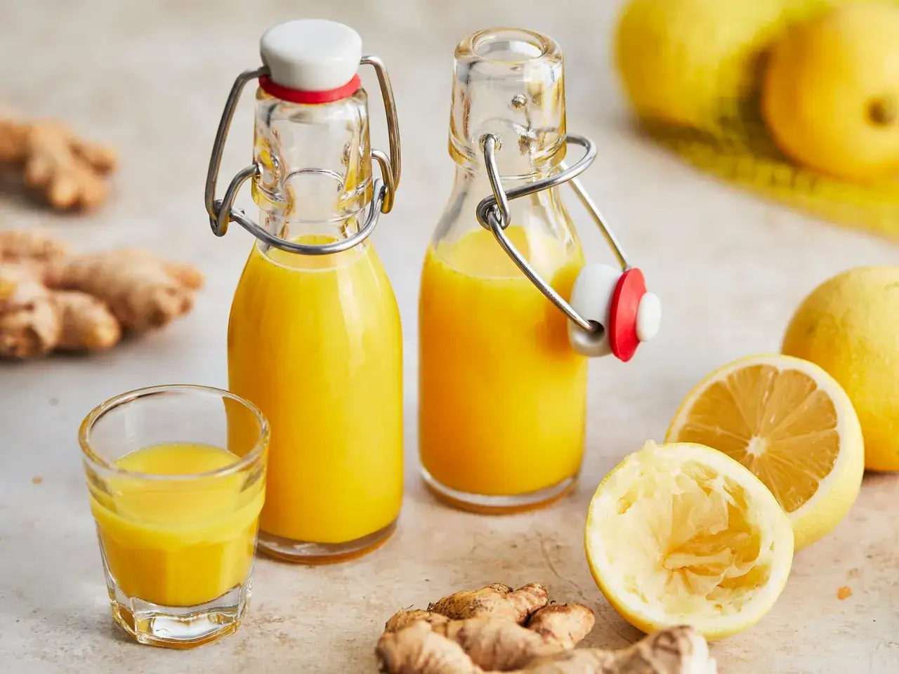 Zwei Flaschen mit leuchtend gelbem Saft, bereit zum Genie&szlig;en. Perfekt, um **Ingwer Shots selber machen** zu lernen und sich etwas Gutes zu tun.