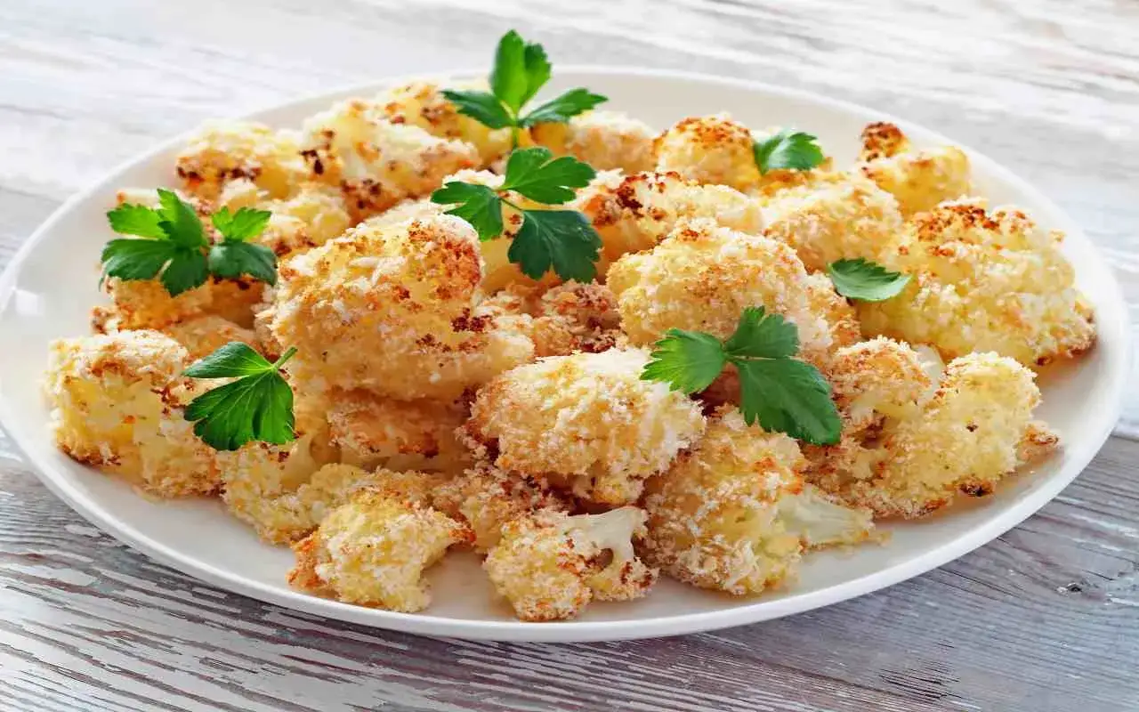 Cavolfiore al forno con pangrattato e formaggio, dorato e croccante, guarnito con prezzemolo fresco.