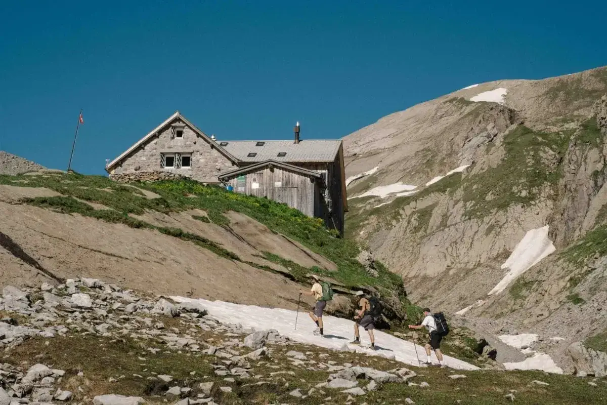 Trois randonneurs progressent sur un sentier enneigé vers un refuge de montagne, une étape de leur randonnée boucle 4 jours Pyrénées.