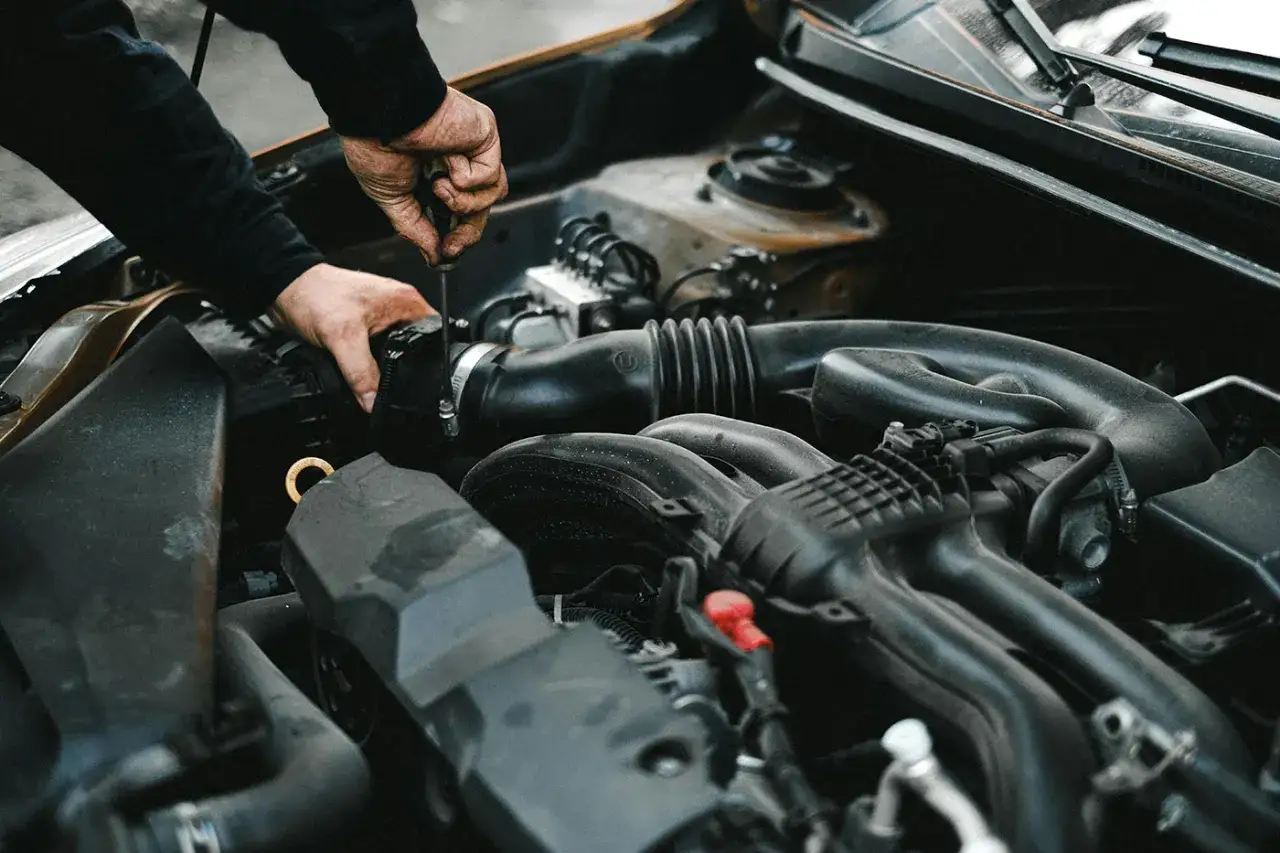 Mano ajustando componente en motor. &iquest;Como saber si es la bateria o el alternador?