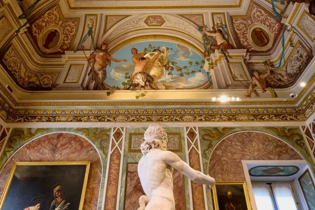 Wnętrze Galleria Borghese z rzeźbą i malowidłami na suficie. Złote zdobienia i freski tworzą bogatą atmosferę.