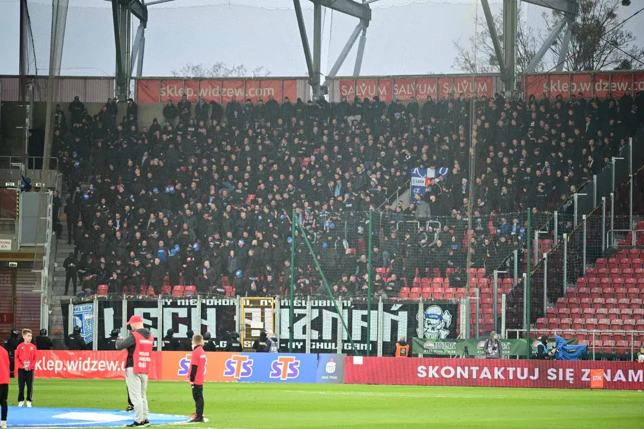 Tłum kibic&oacute;w na trybunach podczas meczu **Widzew Ł&oacute;dź &ndash; Lech Poznań**. Widać transparenty z nazwami klub&oacute;w i logotypami sponsor&oacute;w.