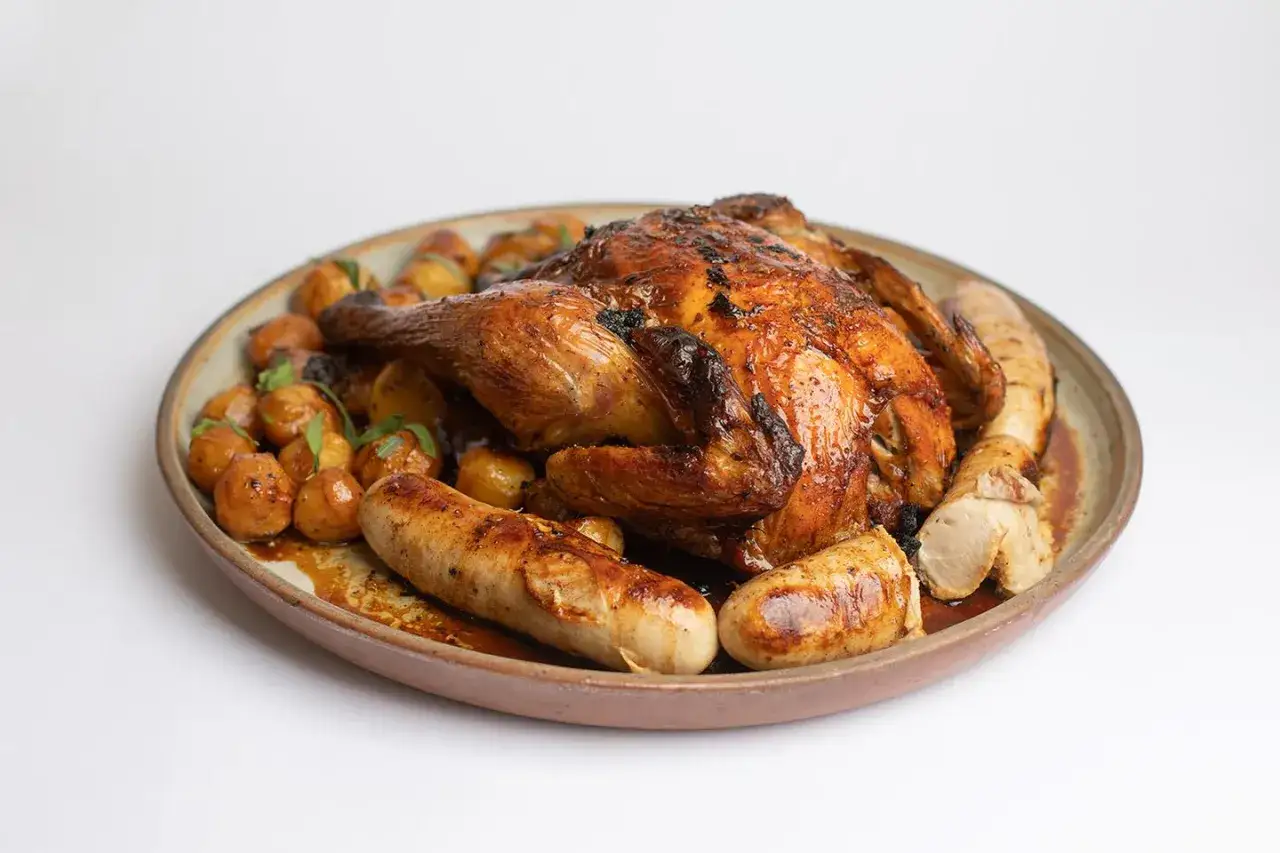 Un plat de f&ecirc;te : poulet r&ocirc;ti dor&eacute;, pommes de terre grenaille et saucisses, une d&eacute;licieuse farce poulet avec abats.