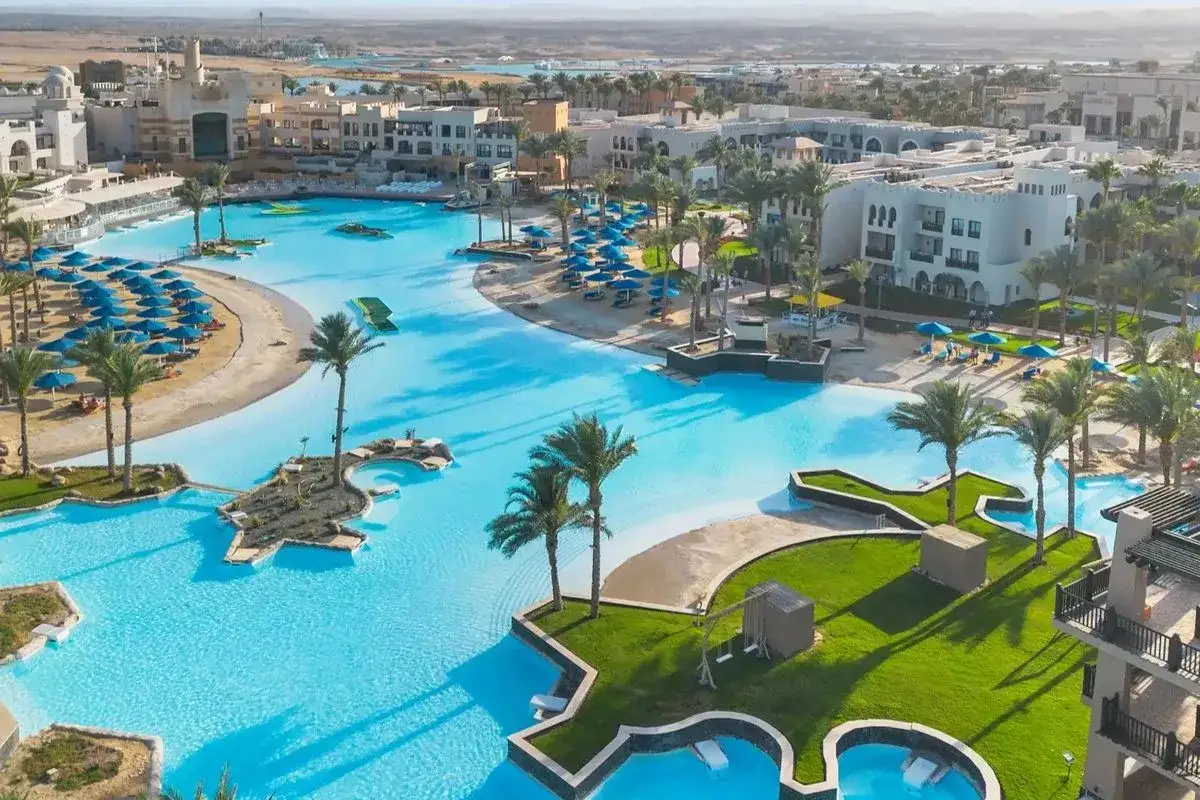 Luksusowy resort z basenami i palmami w Port Ghalib. Piękny, błękitny basen otoczony białym piaskiem i zielenią.