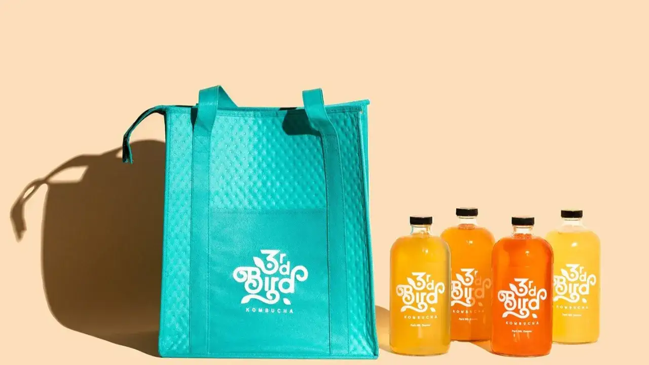 Turkusowa torba i cztery butelki kombuchy 3rd Bird. Zastanawiasz się, jak smakuje kombucha? Spr&oacute;buj tych orzeźwiających napoj&oacute;w!