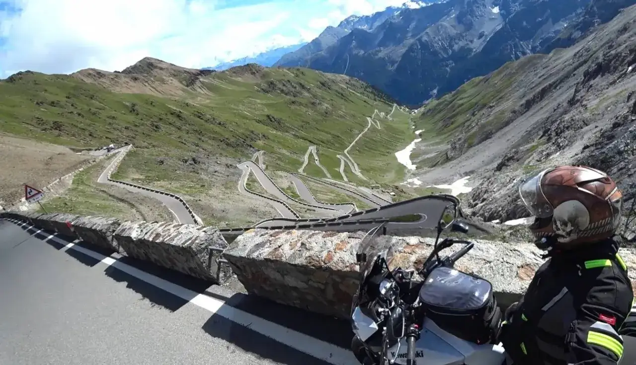 Motocyklista podziwia serpentyny na przełęczy Stelvio. Droga, choć zamknięta, zachwyca widokiem.