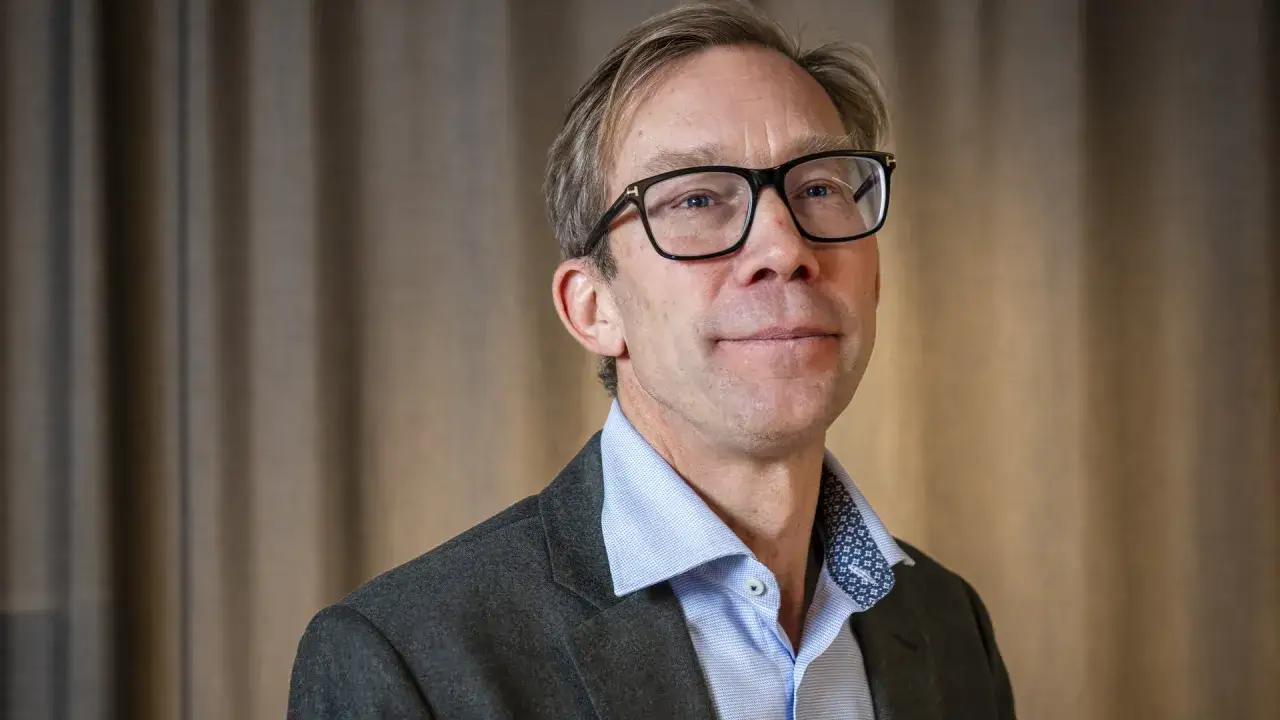 Stefan Krook, en man med glasögon, bär en kavaj och ljusblå skjorta.