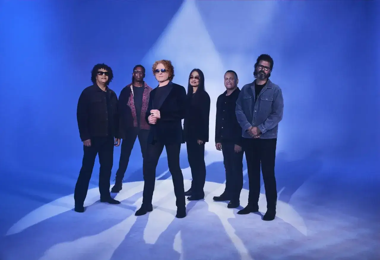 Zespół Simply Red na tle niebieskiej sceny, gotowy do koncertu.