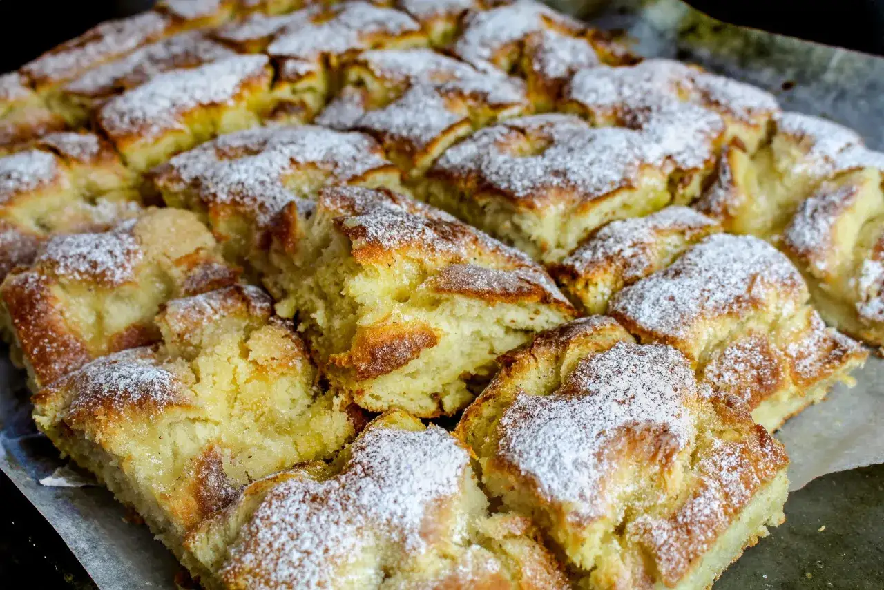 Nybakade bullar p&aring; bakpulver, pudrade med florsocker, ligger p&aring; ett bakpl&aring;tspapper.