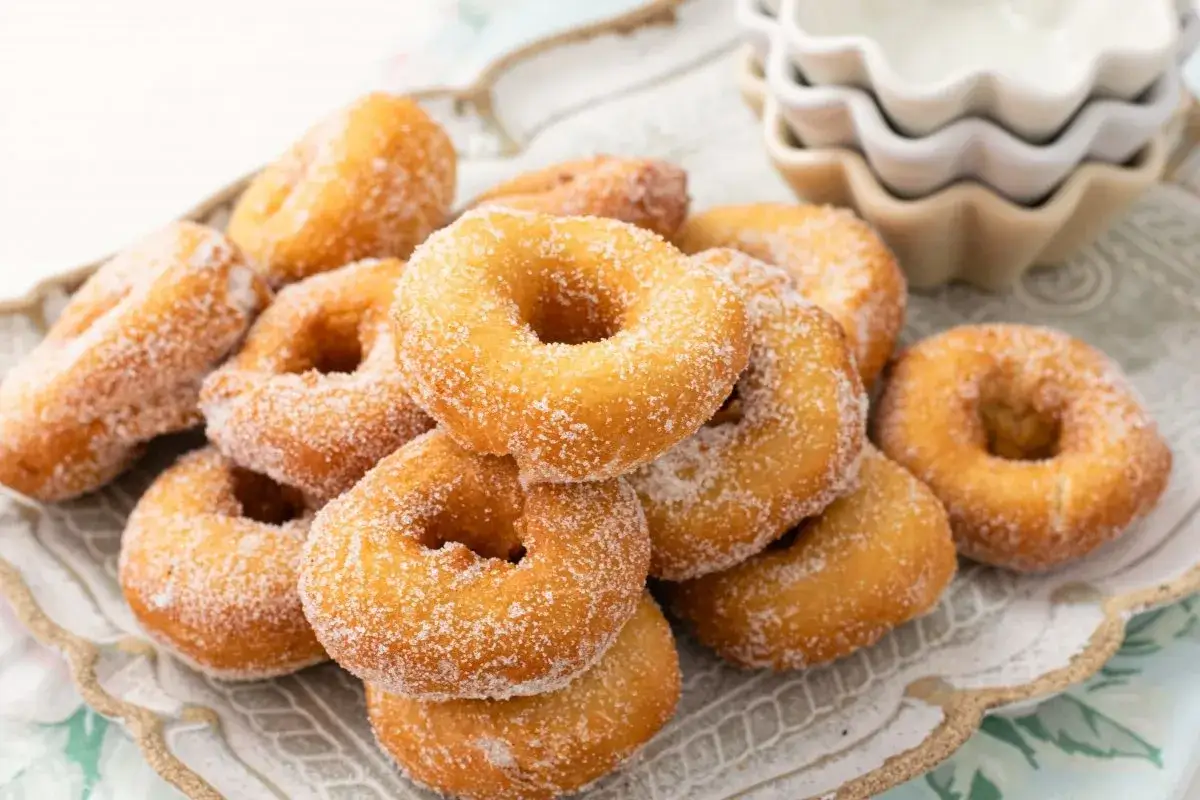 Un montón de rosquillas caseras de toda la vida, doradas y espolvoreadas con azúcar, listas para disfrutar.