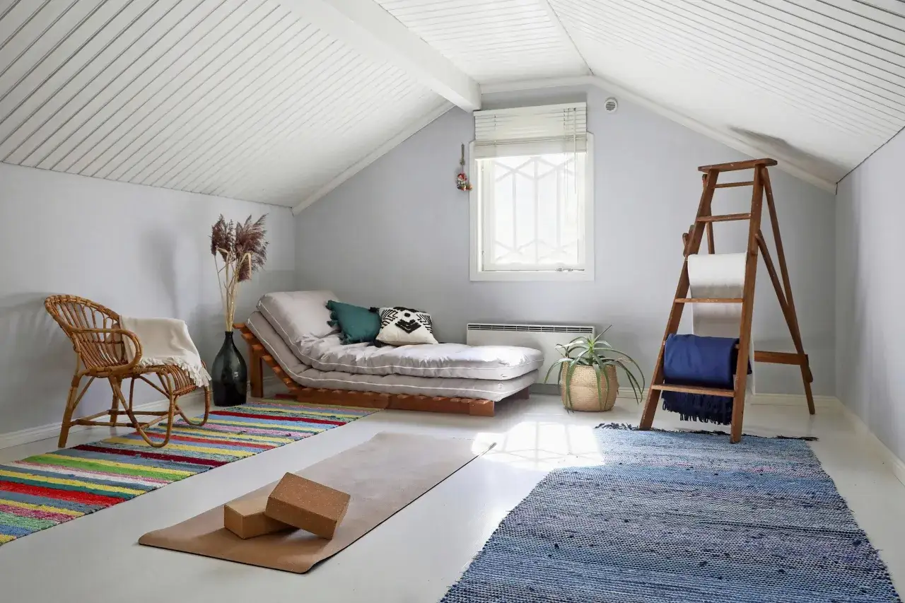 En mysig vrå för ett yin yoga pass. En bäddsoffa, yogamatta med block, en rottingstol och en stege med filtar skapar en lugn atmosfär.